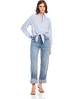 Woman wearing light blue Capri Tie-Front Blouse with long sleeves and V-neck paired with rolled-up jeans and sandals.