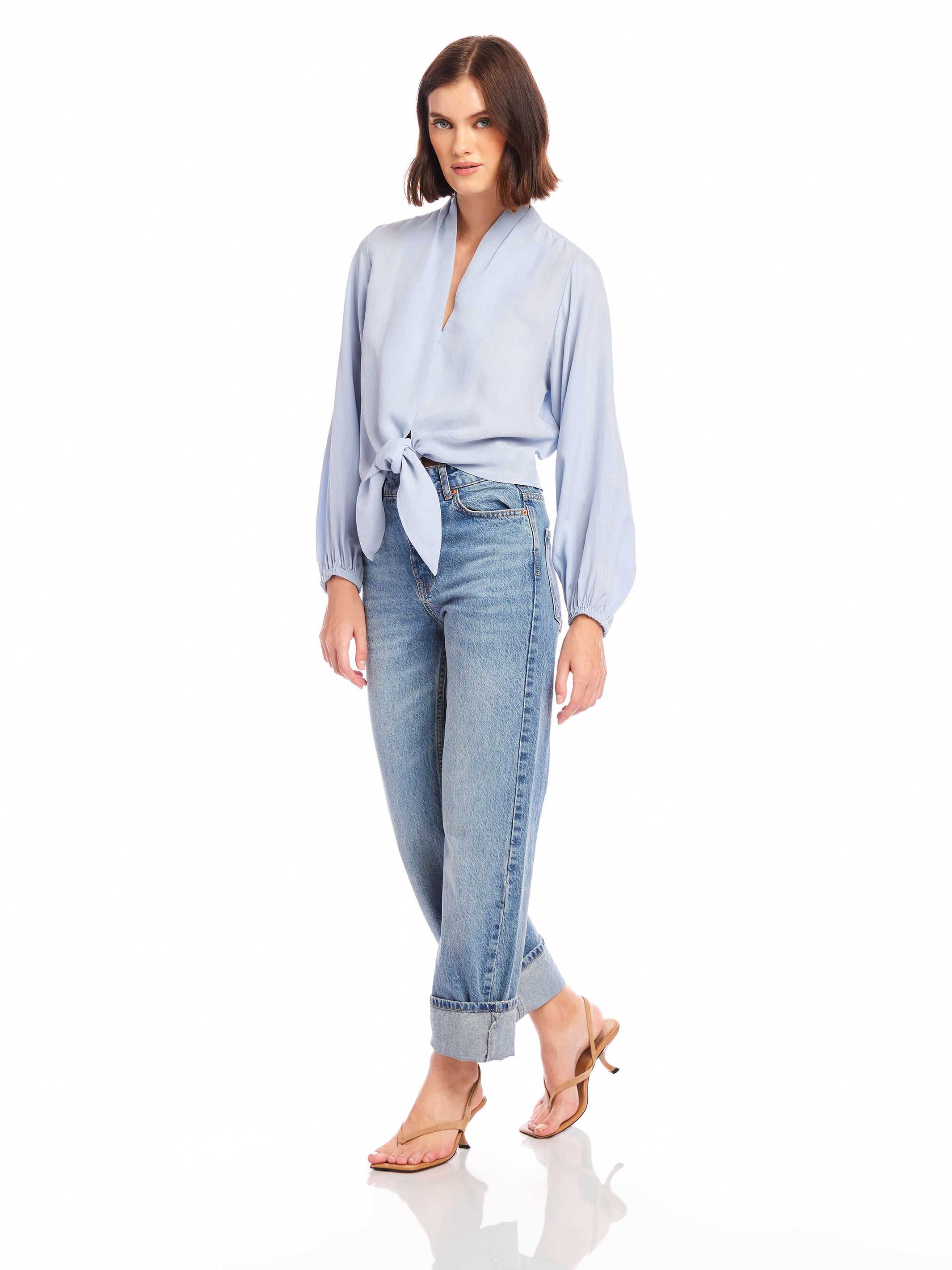 Woman wearing light blue Capri Tie-Front Blouse with long sleeves and denim jeans
