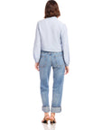 Woman wearing a light blue Capri Tie-Front Blouse with long blouson sleeves, elasticized cuffs, paired with cuffed blue jeans and sandals, shown from the back.