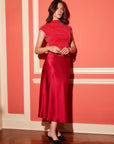 Elegant red satin Brielle Midi Skirt with side slit and elastic waistband modeling at indoor setting