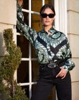 Woman wearing Chloe Blouse with Florence scarf satin print and long bishop sleeves, paired with black pants and sunglasses.