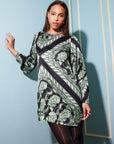Woman wearing green and black patterned Juliette Mini Dress with long blouson sleeves and boatneck style