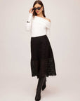 Woman wearing black Millie A-Line Skirt with scalloped stretch lace and white off-shoulder top