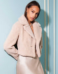 Woman wearing Iva Cropped Sherpa Jacket in soft beige with a notch collar and button front closure