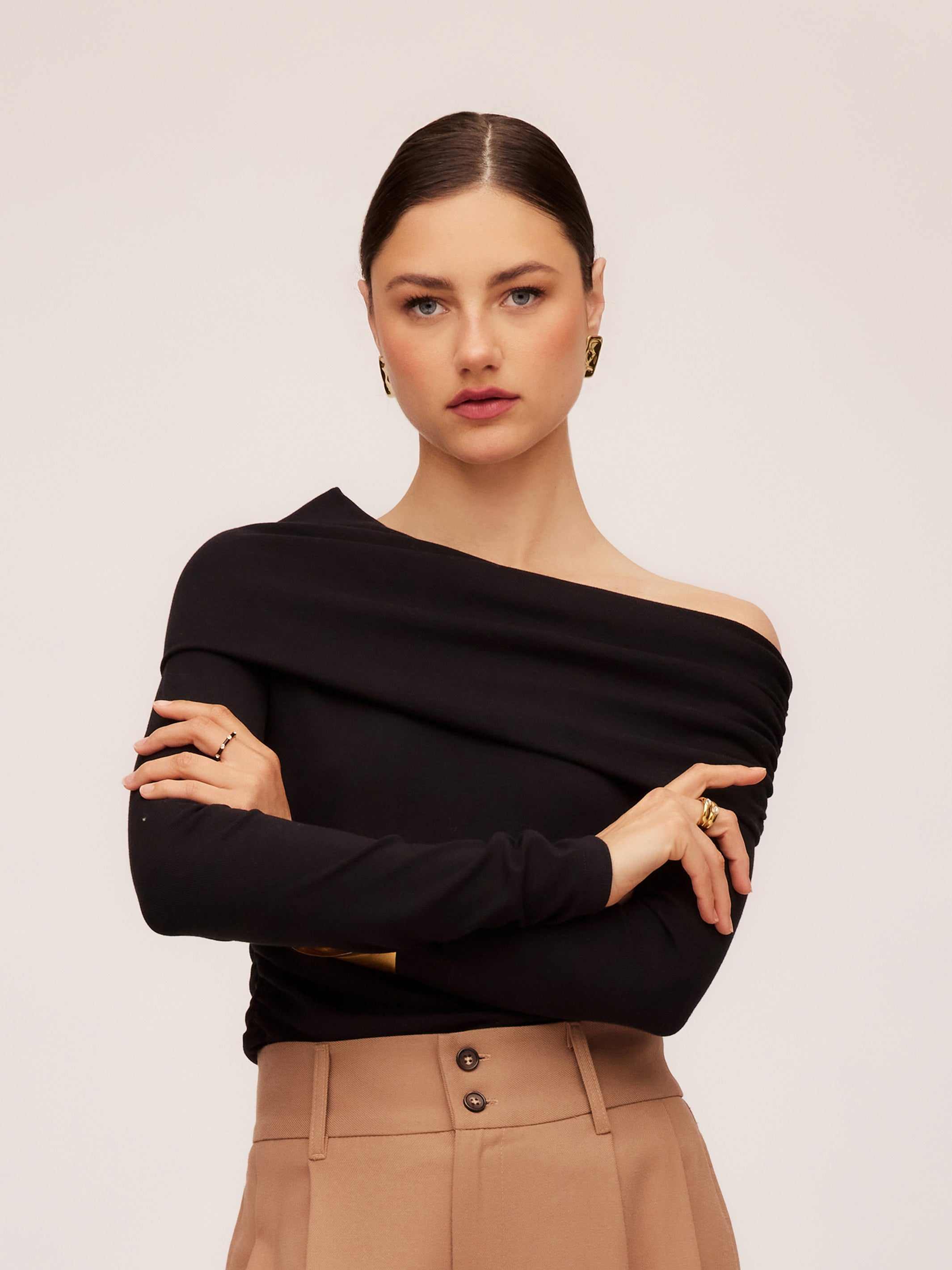 Woman wearing black asymmetric one-shoulder long sleeve rib knit top with beige pants