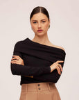 Woman wearing black asymmetric one-shoulder long sleeve rib knit top with beige pants