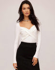 Woman wearing white Zelda Crossover Top with long sleeves and sweetheart neckline paired with black skirt
