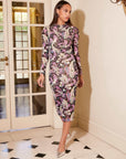 Woman wearing a ruched Selena midi dress with Italian paisley mesh fabric and long sleeves in a chic indoor setting