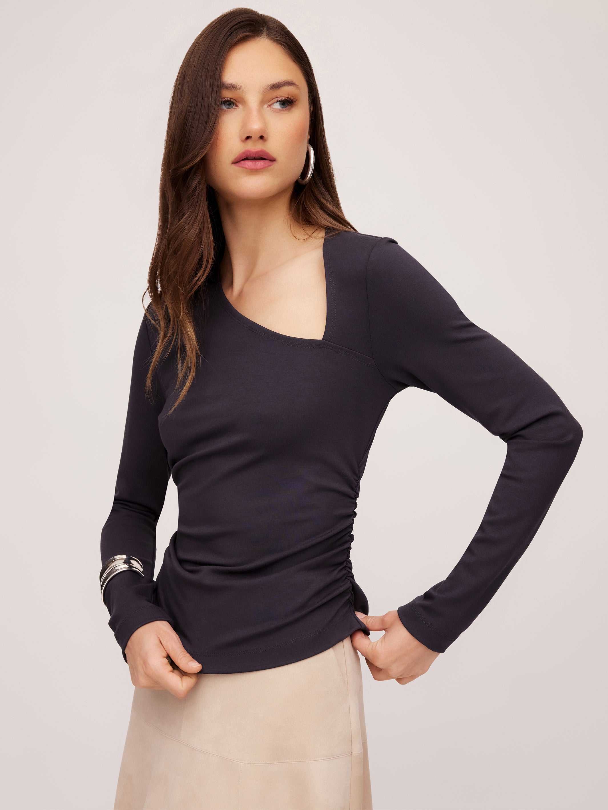 Woman wearing black Shay Asymmetric Shirred Top with long sleeves and side shirring detail