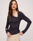 Woman wearing black Shay Asymmetric Shirred Top with long sleeves and side shirring detail