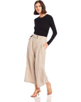 Woman wearing beige pinstripe linen Sadie Trousers with wide leg and cropped length paired with black long-sleeve top