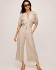 Woman wearing beige pinstripe linen Sadie Trousers with a wide leg and cropped length, styled with a light blouse and sunglasses.
