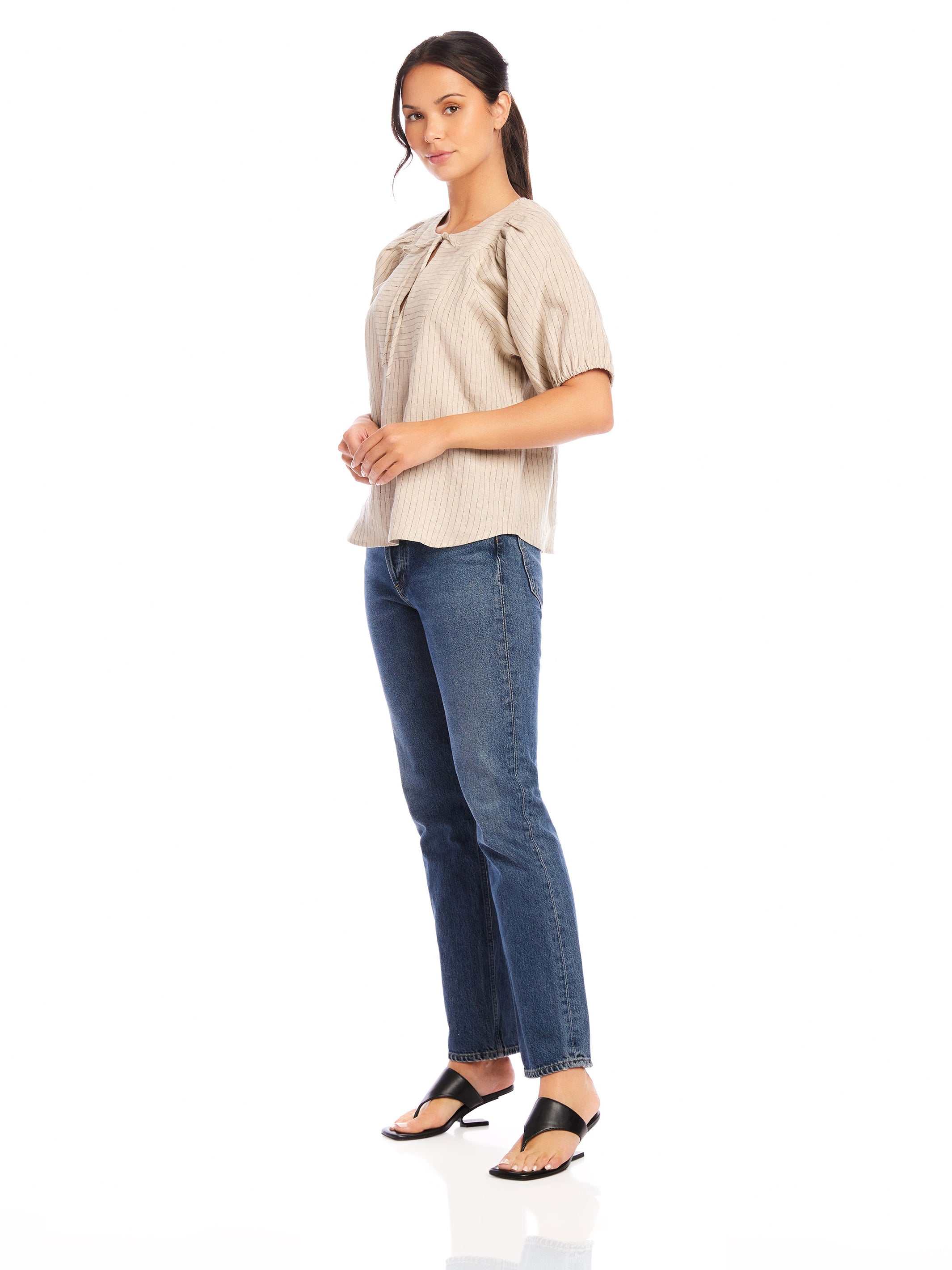 Woman wearing beige Imogen Poof Sleeve Top with pinstripe linen and blue jeans.