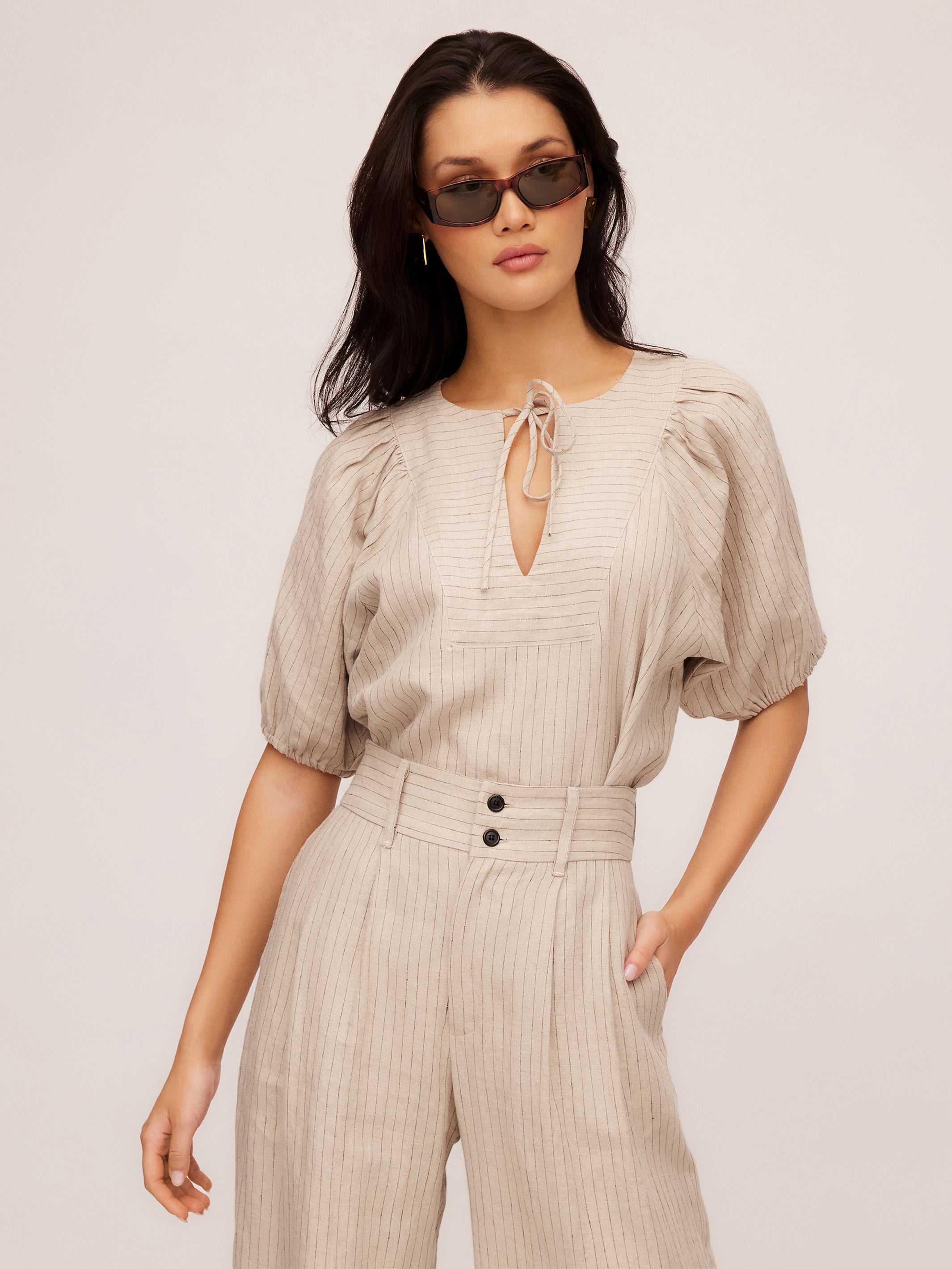 Woman wearing Imogen Poof Sleeve Top in lightweight pinstripe linen with split neck tie and short elasticized sleeves