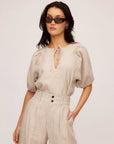 Woman wearing beige Imogen Poof Sleeve Top with pinstripe linen and matching high-waist trousers