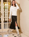 woman wearing black Brielle midi skirt with side slit and white long sleeve top indoors