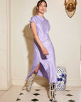Woman wearing a lilac Brielle Midi Skirt with an A-line silhouette and side slit paired with silver boots in an elegant interior setting