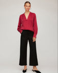 Woman wearing black Rylee Cropped Pants with a red blouse and black flats on a neutral background
