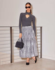 Woman wearing Kari Crossover Top in dark rib knit with cutout neckline and long sleeves paired with leopard print skirt and black handbag