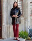 Woman wearing black faux patent leather jacket with button front and collar outdoors
