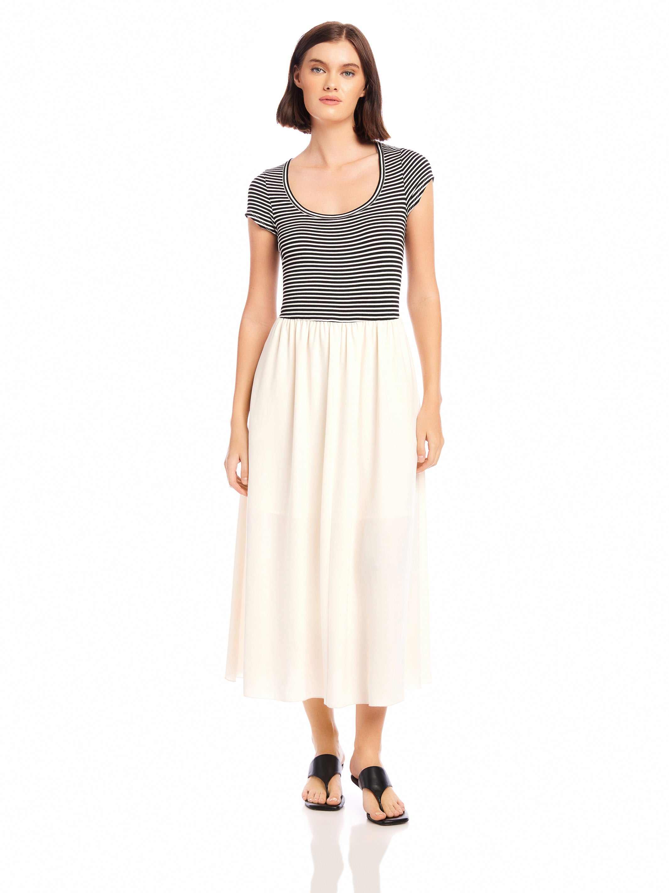 Woman wearing Contrast Hem Sylvie Dress with black and white striped jersey top and solid cream skirt, short cap sleeves, and side pockets.