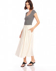 Woman wearing a Contrast Hem Sylvie Dress with a striped black and white jersey top and a contrasting cream skirt with side pockets and short cap sleeves.