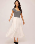 Woman wearing Contrast Hem Sylvie Dress with black and white striped top and flowing white skirt.
