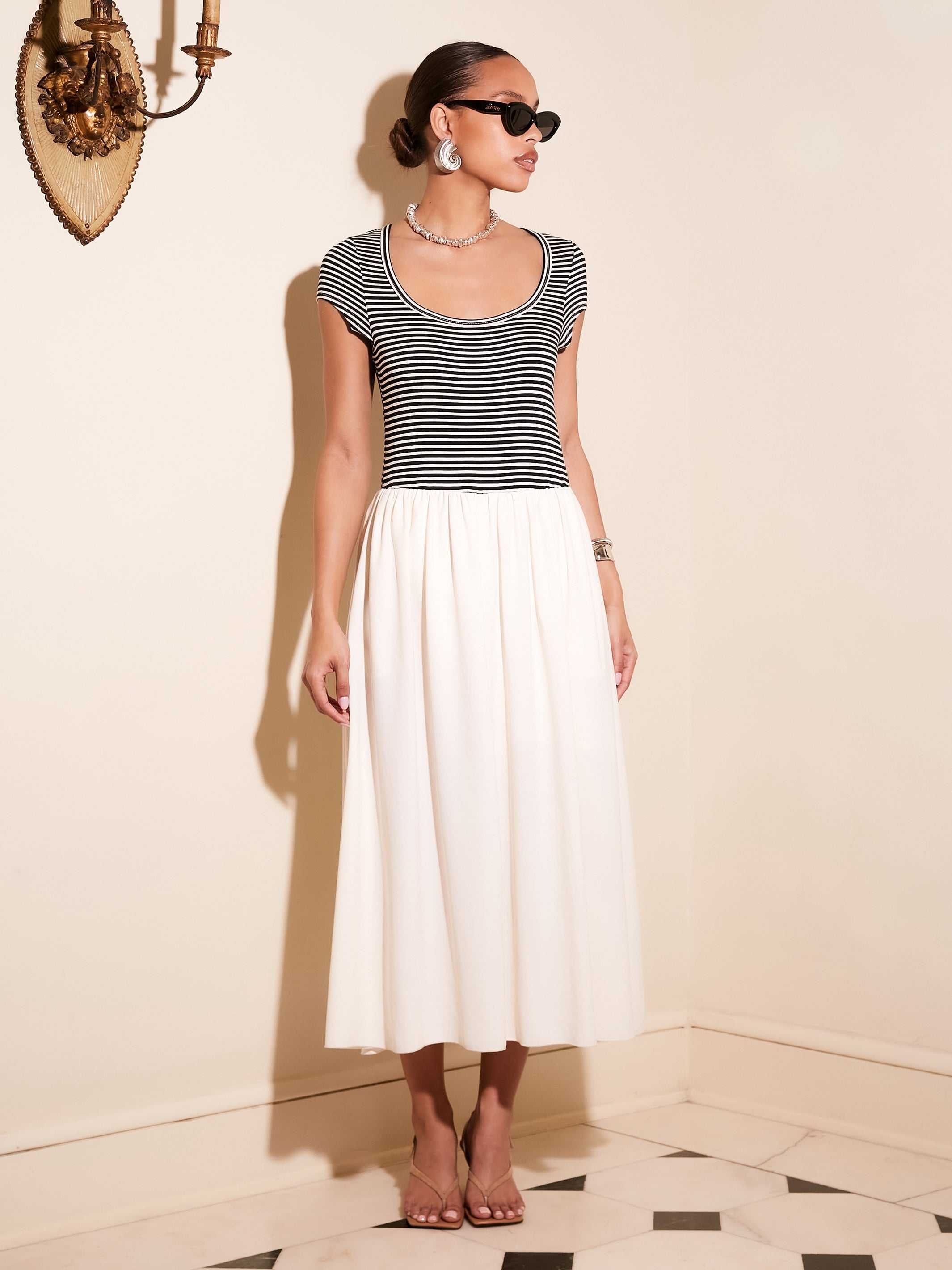 Contrast Hem Sylvie Dress with black striped jersey top and white skirt, short sleeves, scoop neck, side pockets, styled with sunglasses and earrings.