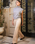 Woman wearing light brown Ellie Bootcut Pants with pintuck detail and sleeveless gray turtleneck top walking outdoors