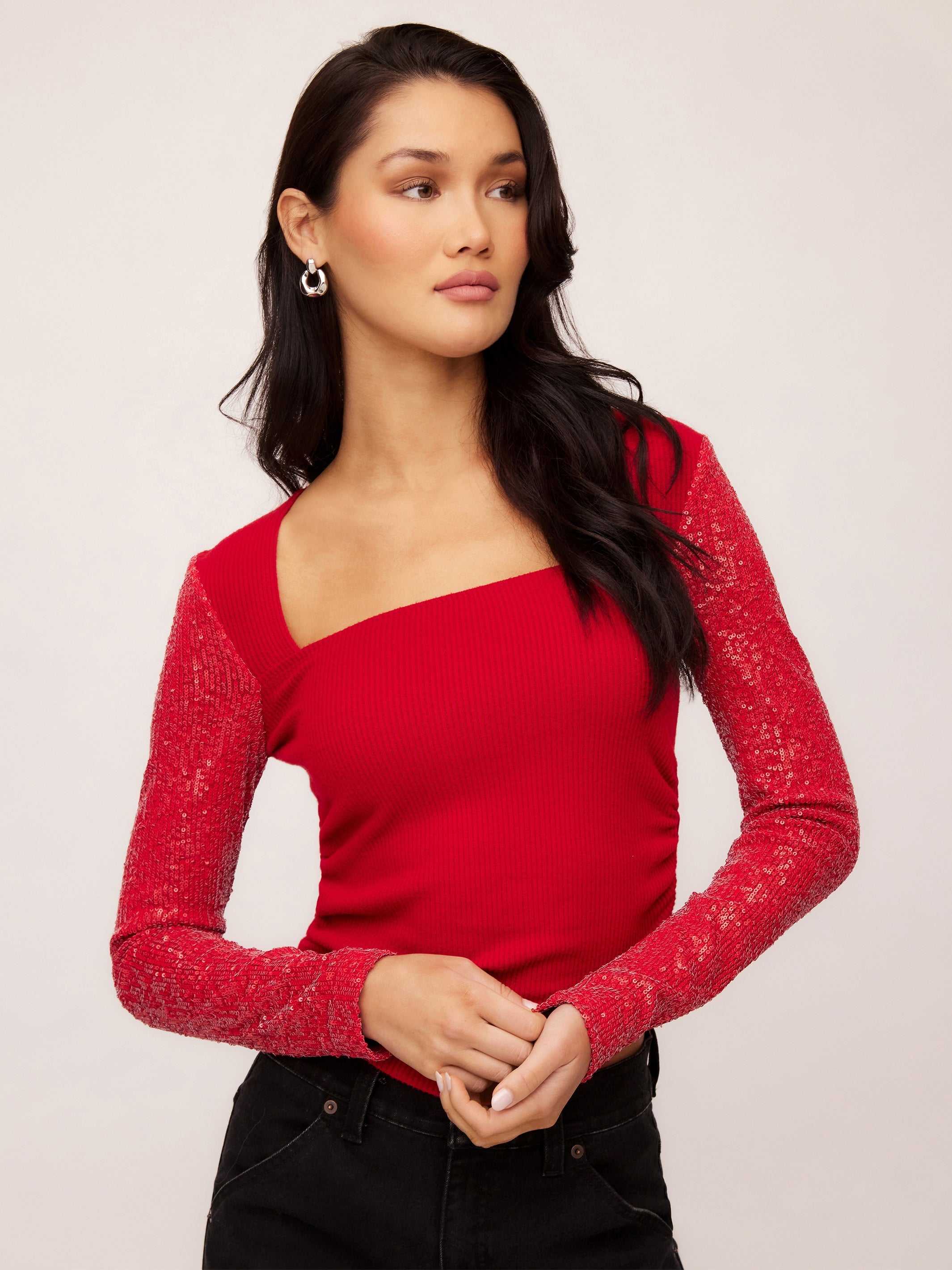 Woman wearing red Cady Contrast Sequin Top with ribbed knit body and sparkly sequin mesh long sleeves