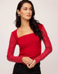 Woman wearing red Cady Contrast Sequin Top with ribbed knit body and sparkly sequin mesh long sleeves