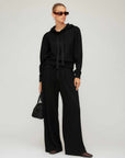 Woman wearing Jenny Pleated Pants with elastic waistband and drawstring tie in a relaxed, wide-leg style