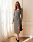 Woman wearing Tyler Side-Twist Dress with black and white stripes, long sleeves, scoop neckline, side twist waist detail, and side slit.
