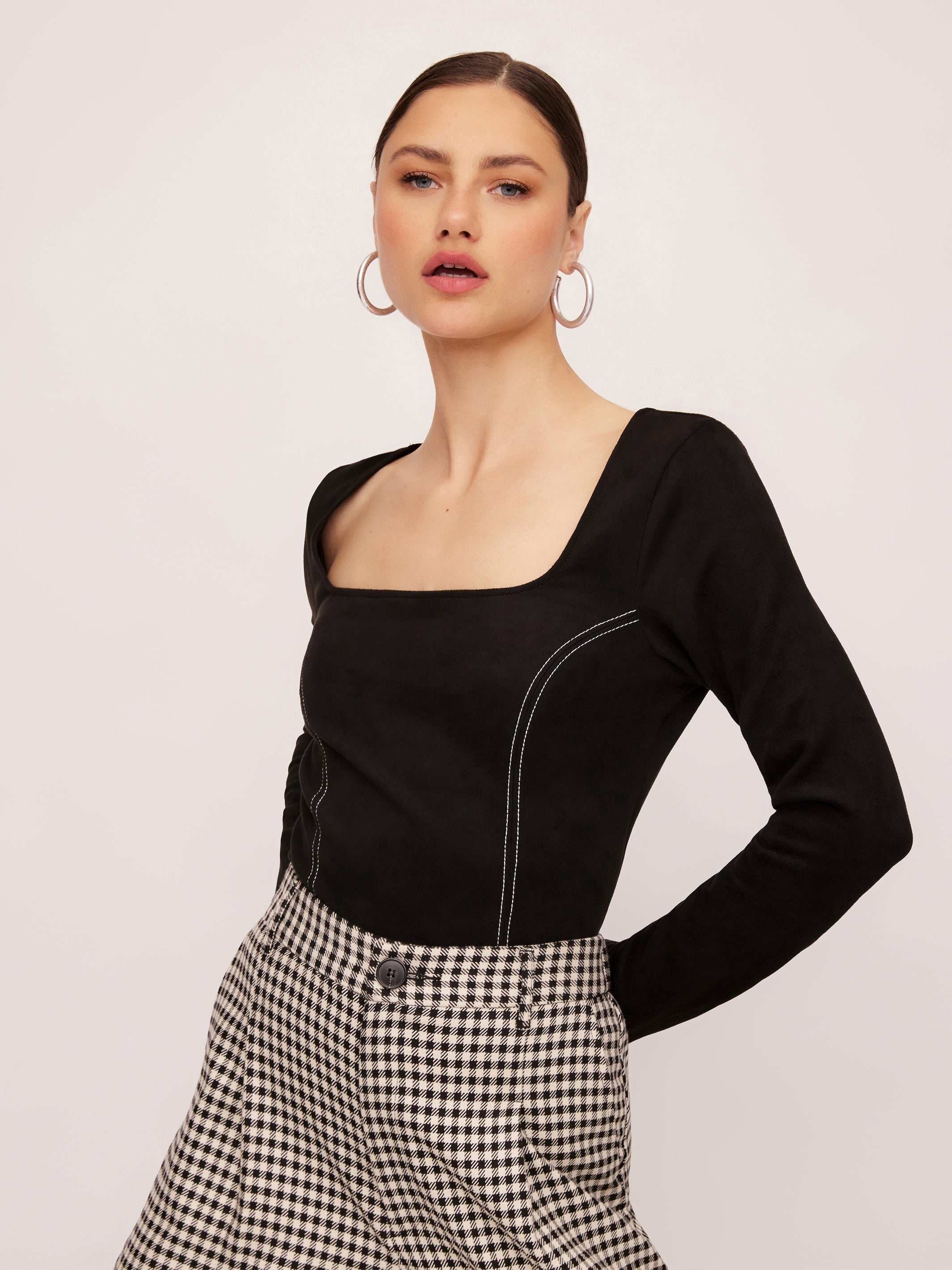 Black faux suede stitch top with long sleeves and square neck worn by a model