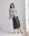 Woman wearing gray Astrid Cardigan Sweater with Nordic pattern and dark skirt in bright room