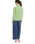 Back view of woman wearing sage green Claudia turtleneck sweater with wide rib detail and side slits, paired with blue jeans.