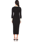 Back view of a woman wearing a long black Maves Dress with white cuffs and collar, featuring a crew neck and button-down front design.