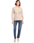 Woman wearing beige Lucy Cardigan with double-breasted buttons and wide cuffs paired with blue jeans and silver heels