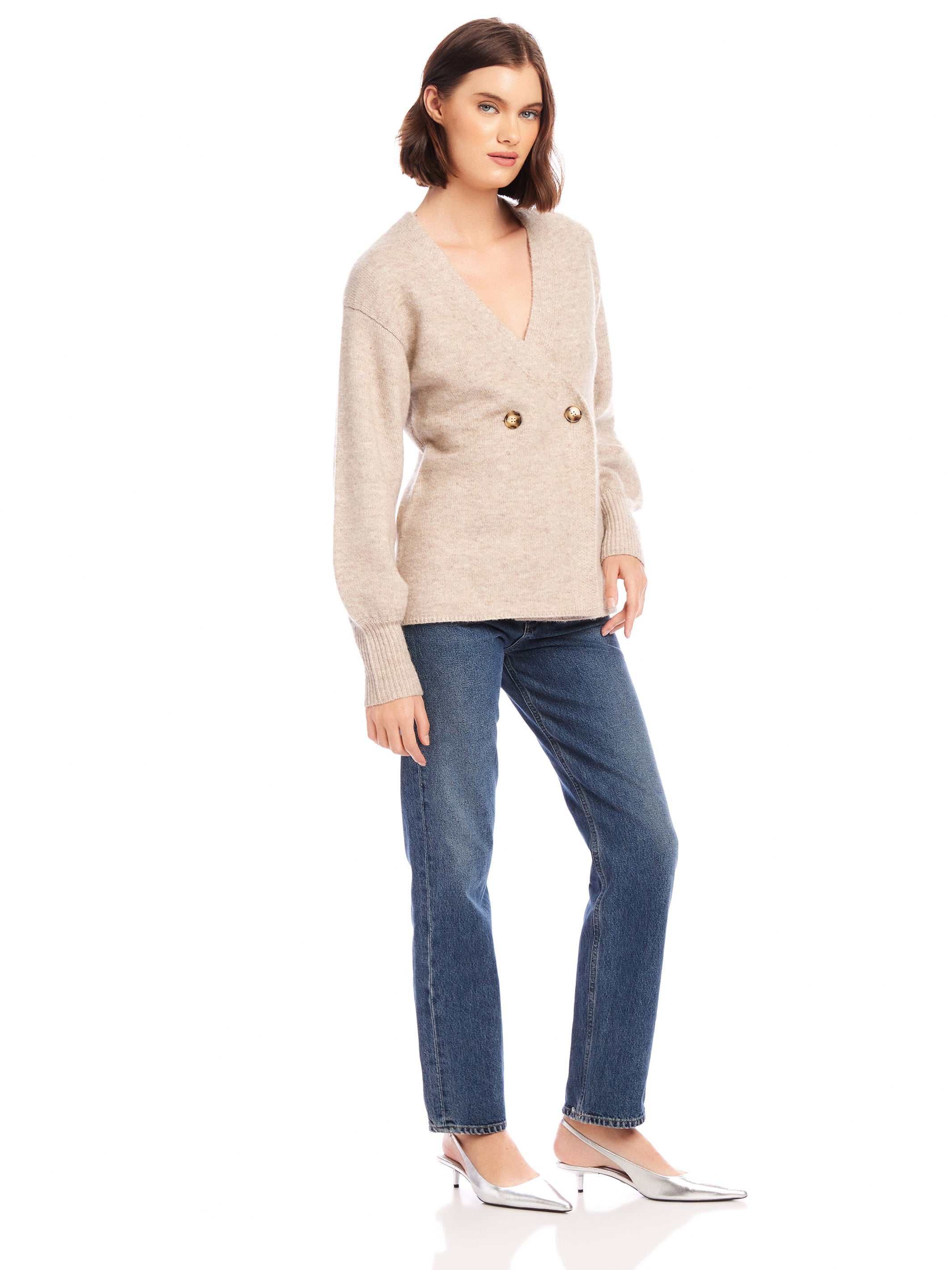 Woman wearing Lucy Cardigan with double-breasted buttons and wide cuffs paired with blue jeans and silver heels