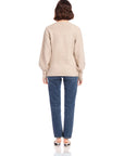 Back view of a woman wearing a beige Lucy Cardigan with long blouson sleeves and wide cuffs paired with blue jeans and heels