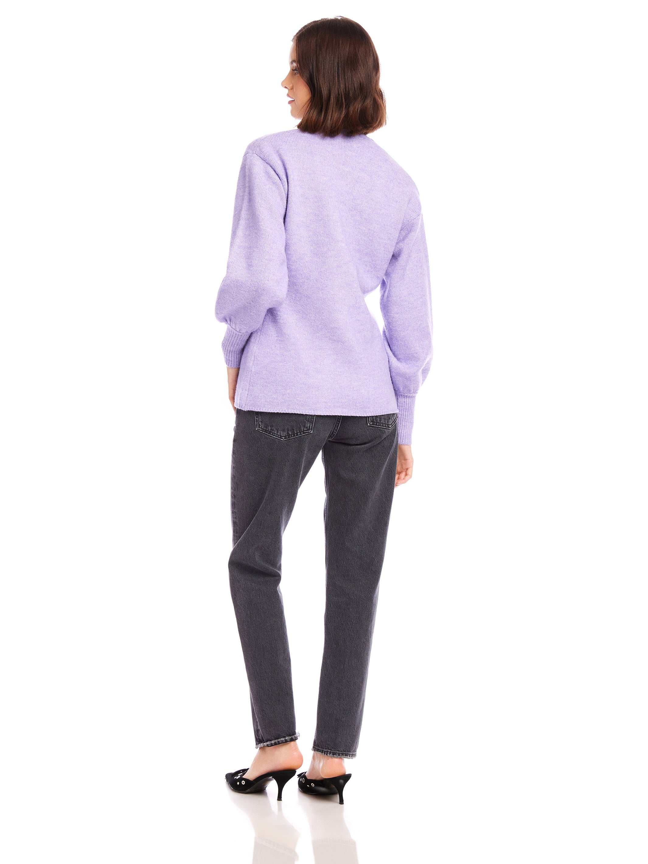 Woman wearing lavender Lucy Cardigan with long blouson sleeves and wide cuffs, paired with black jeans and black heels, viewed from the back