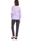 Woman wearing lavender Lucy Cardigan with long blouson sleeves and wide cuffs, paired with black jeans and black heels, viewed from the back
