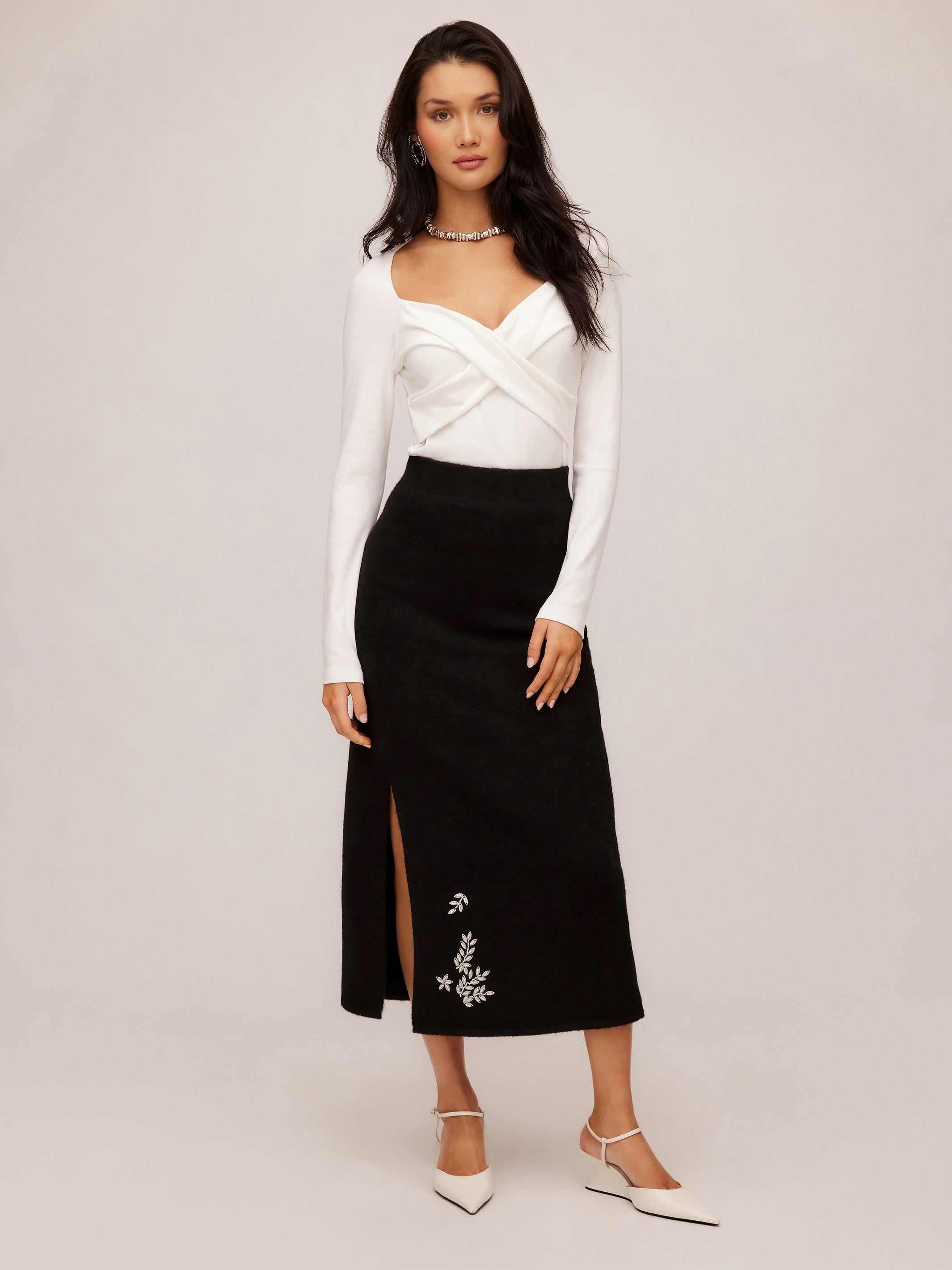 woman wearing black Brett embellished sweater skirt with beaded leaf embroidery and front slit paired with white long sleeve top