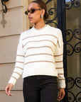 Woman wearing a white and beige striped Luca Crewneck Sweater with wide ribbed hem and cuffs and long drop shoulder sleeves.