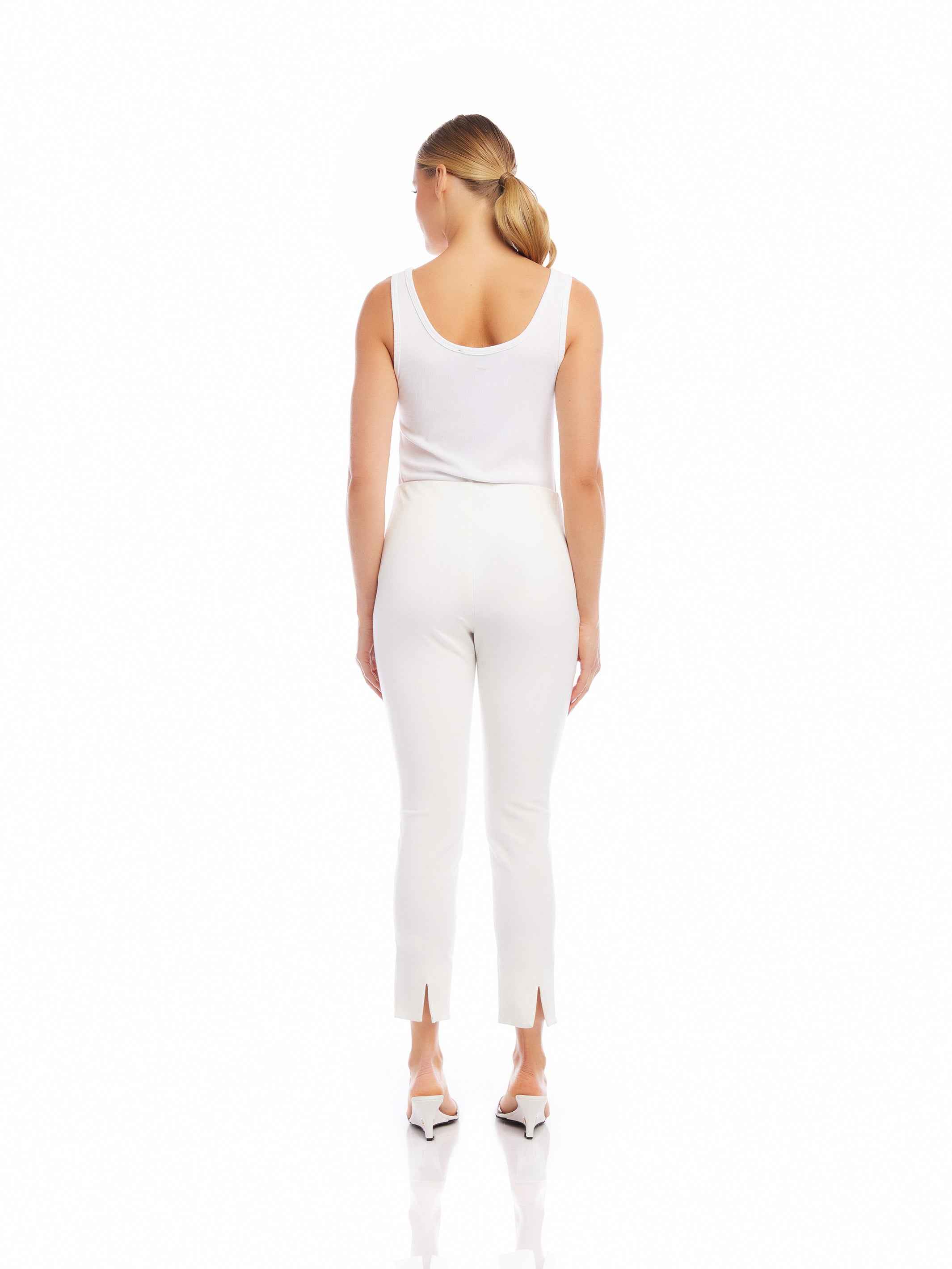 Woman wearing white ankle slit pants with elastic waistband and white sleeveless top viewed from back