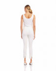Woman wearing white ankle slit pants with elastic waistband and white sleeveless top viewed from back