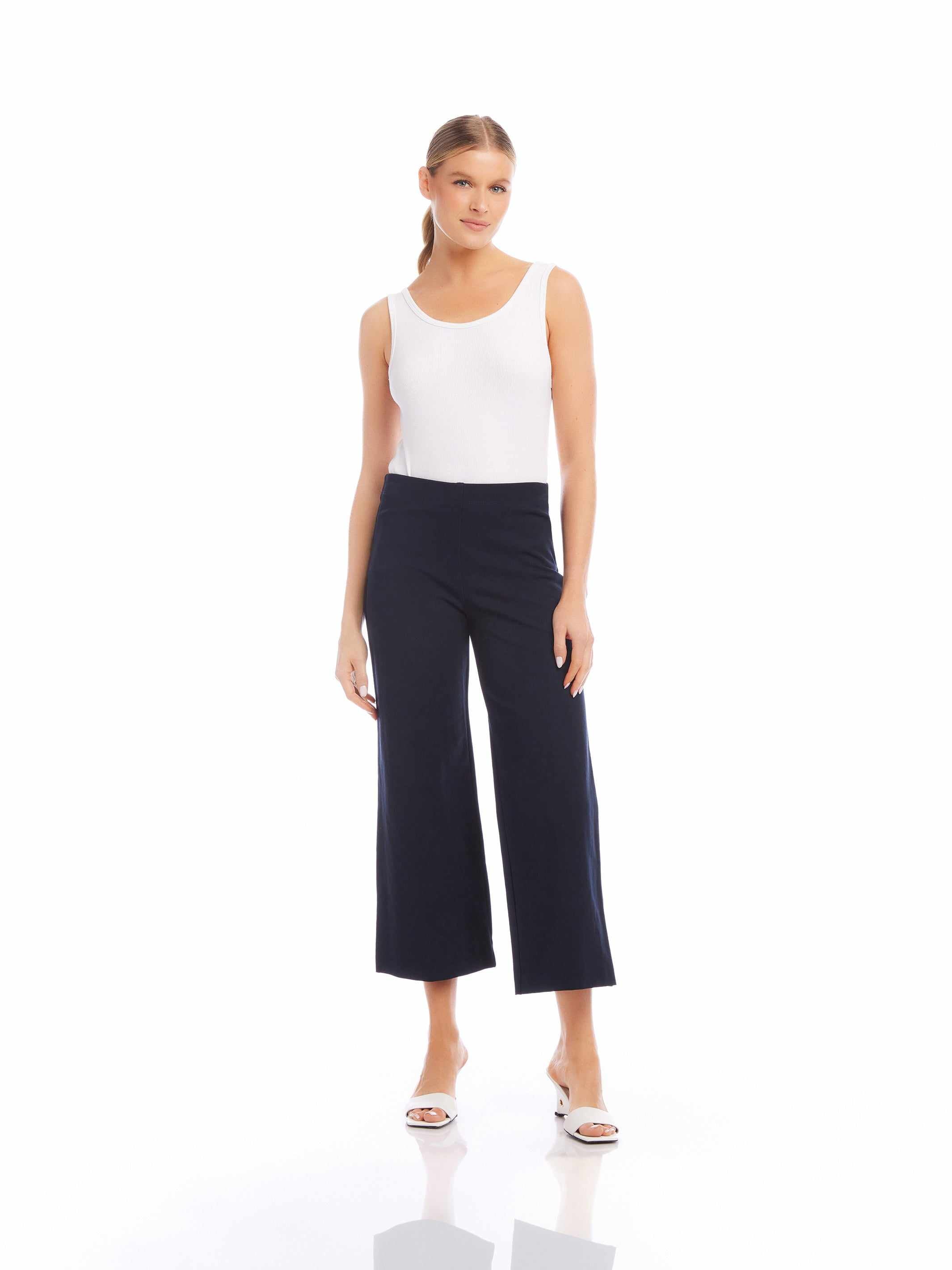 Woman wearing black wide-leg cropped pants with a white sleeveless top and white heels