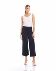 Woman wearing black wide-leg cropped pants with a white sleeveless top and white heels