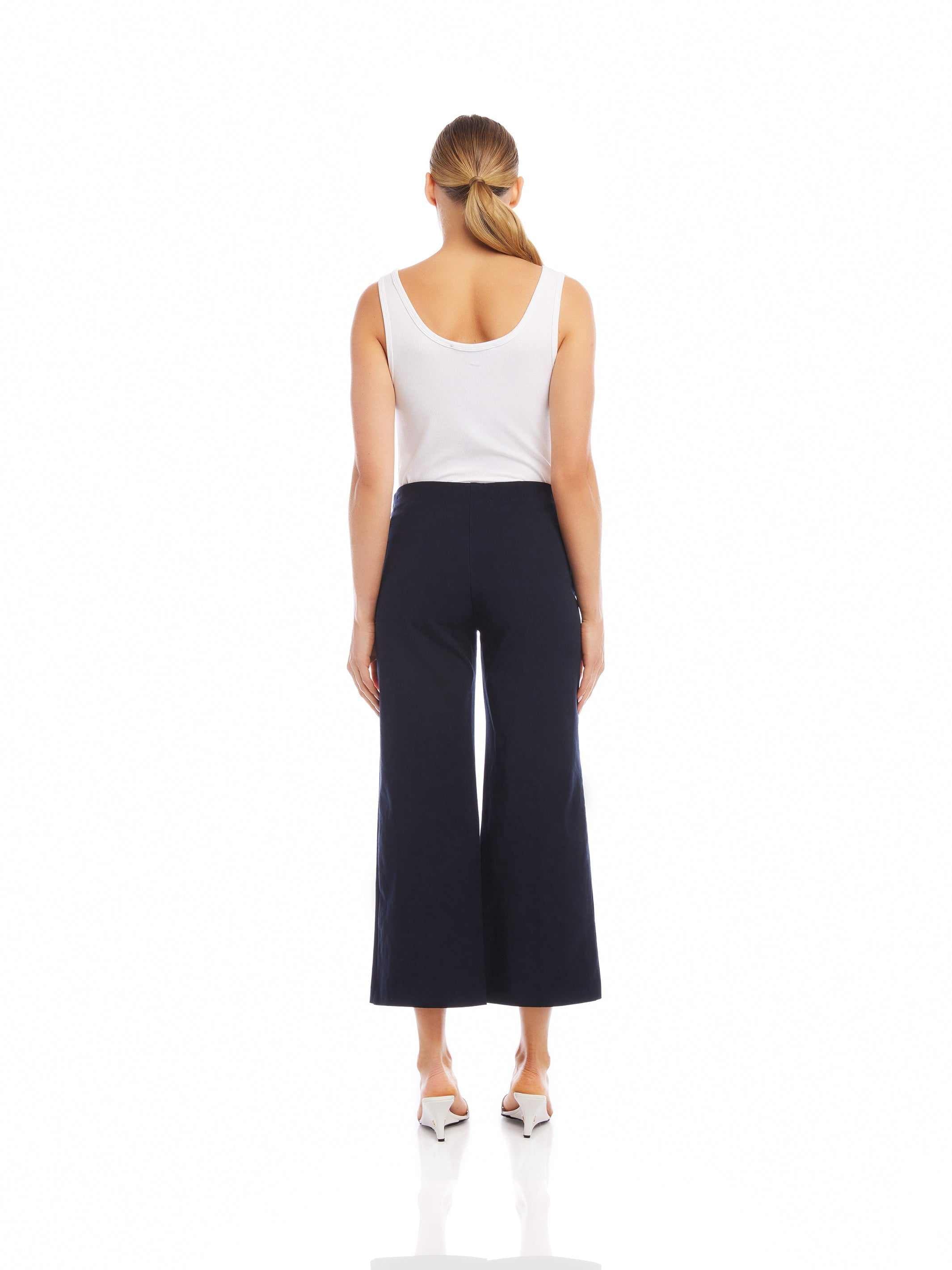 Woman wearing black wide-leg cropped pants with elastic waistband and white sleeveless top, back view
