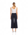 Woman wearing black wide-leg cropped pants with elastic waistband and white sleeveless top, back view